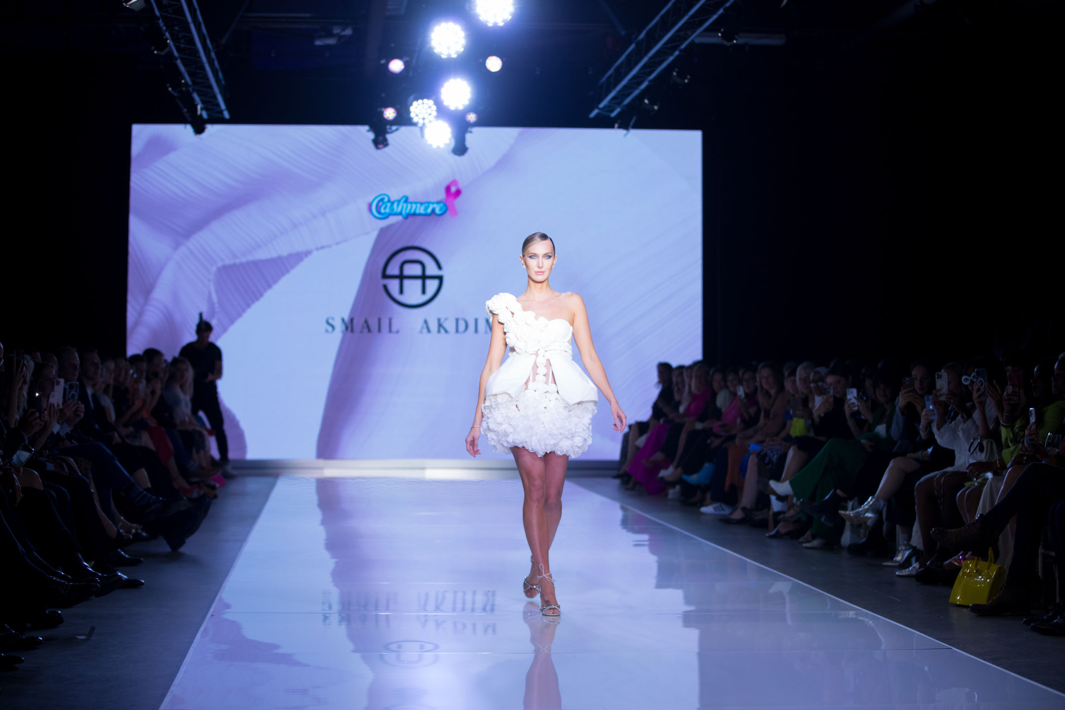 A model walking down a runway in a white dress